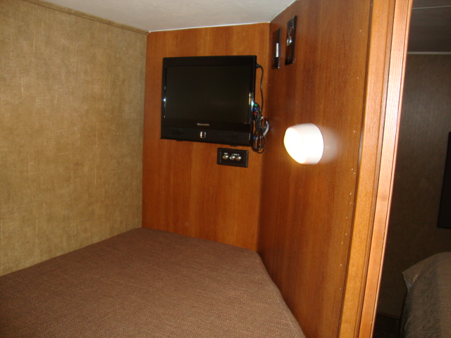 The Coachmen 320BH Class C Bunkhouse features a TV mounted on a wooden wall, adding to the comfort and convenience of the living space