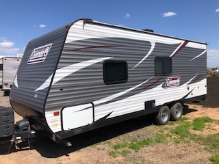 Travel trailer parked in an open space with other RVs nearby, showcasing a camping or parking area