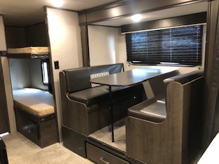 Interior view of a travel trailer, showing the layout and design of the living space, including furniture, appliances, and fixtures